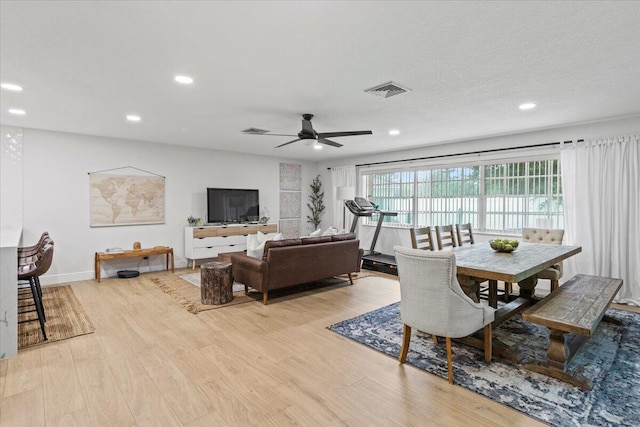 living room featuring light hardwood / wood-style floors, a textured ceiling, and ceiling fan