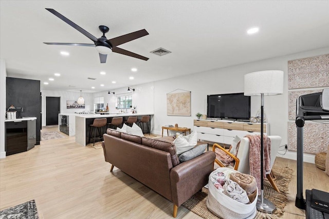 living room with ceiling fan and light hardwood / wood-style floors