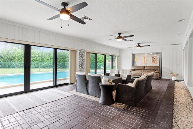 living room featuring a textured ceiling, ceiling fan, and ornamental molding