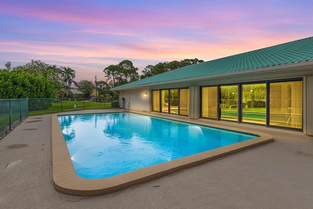 pool at dusk featuring a patio area