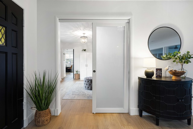 hall featuring a notable chandelier and light hardwood / wood-style flooring