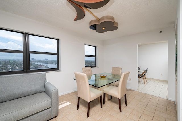 dining area with light tile patterned floors, baseboards, and a textured ceiling