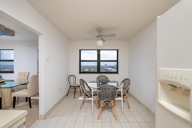 dining area with light tile patterned floors, ceiling fan, and a textured ceiling