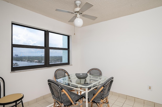 tiled dining room featuring a ceiling fan, a textured ceiling, and baseboards