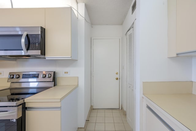 kitchen featuring stainless steel appliances, light countertops, visible vents, light tile patterned flooring, and a textured ceiling