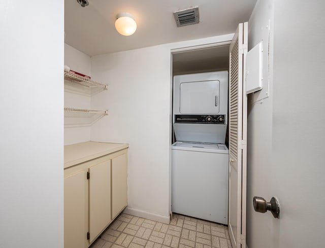 clothes washing area with laundry area, baseboards, visible vents, stacked washer / drying machine, and light floors