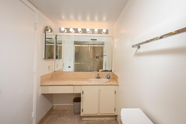 bathroom featuring a stall shower, baseboards, vanity, and toilet