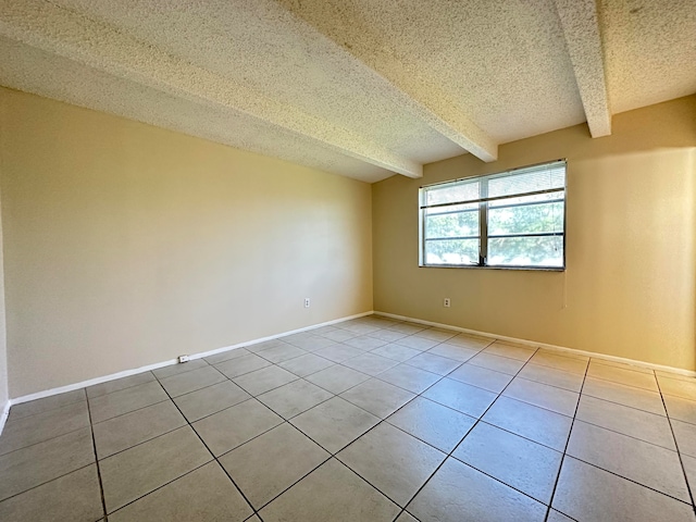 tiled empty room featuring beam ceiling and a textured ceiling