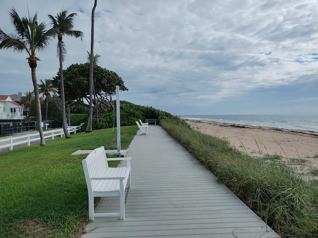 view of property's community featuring a lawn, a view of the beach, and a water view