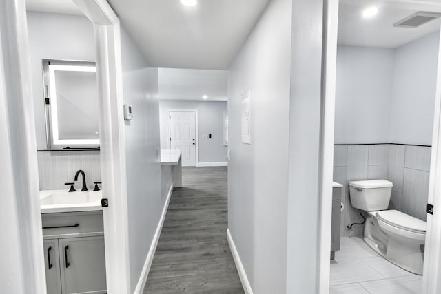 bathroom with vanity, wood-type flooring, tile walls, and toilet