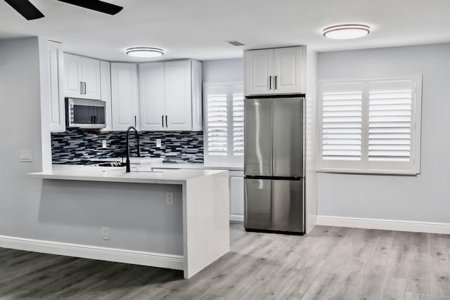 kitchen featuring white cabinets, stainless steel appliances, tasteful backsplash, and sink