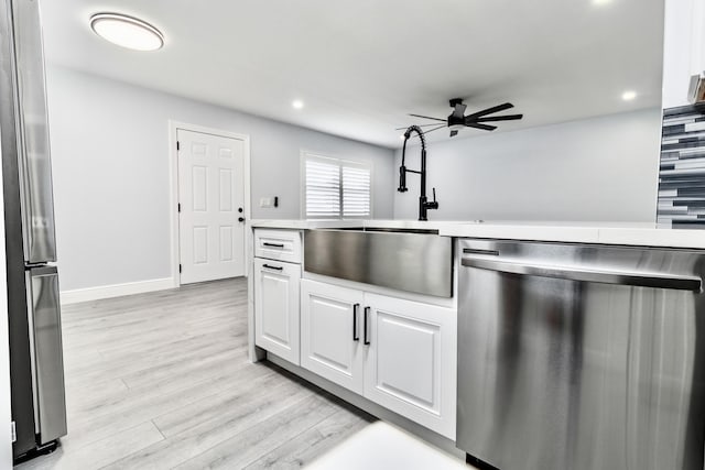 kitchen with white cabinetry, sink, ceiling fan, stainless steel appliances, and light wood-type flooring