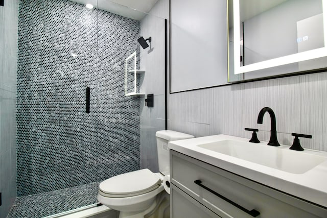 bathroom featuring vanity, toilet, and a shower with shower door