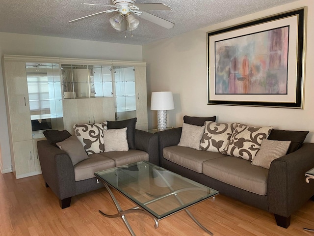 living room with wood-type flooring, ceiling fan, and a textured ceiling