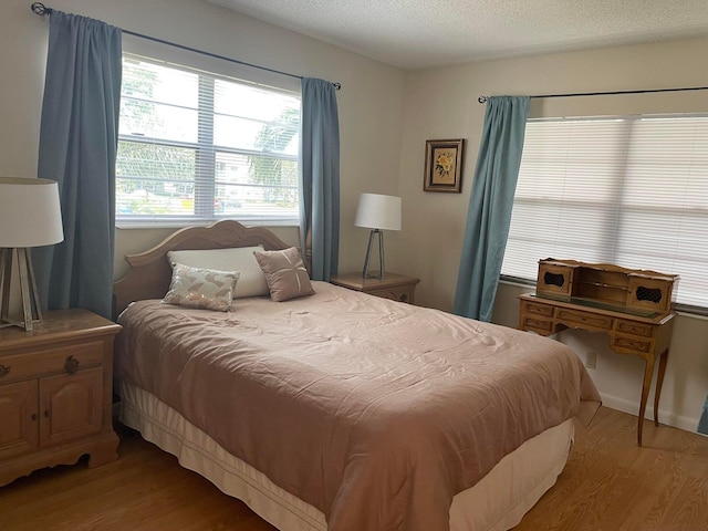 bedroom with hardwood / wood-style flooring, a textured ceiling, and multiple windows