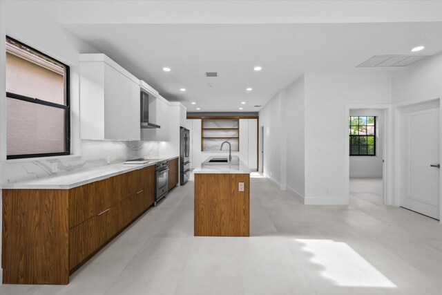 kitchen with stainless steel fridge, backsplash, sink, oven, and an island with sink