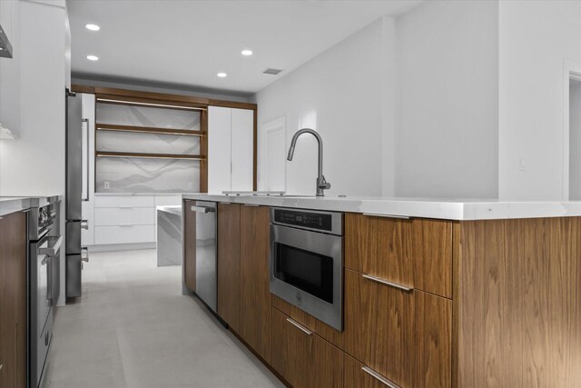 kitchen featuring decorative backsplash, white cabinetry, sink, and appliances with stainless steel finishes