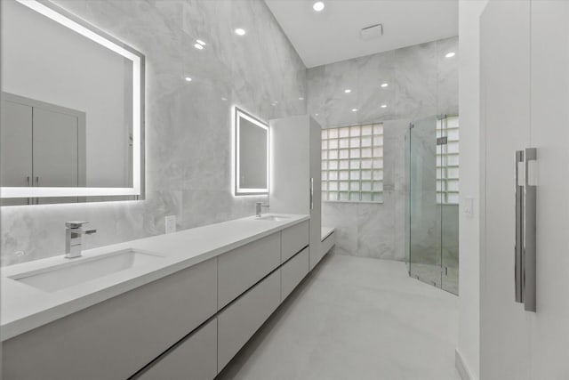 bathroom with a shower with door, vanity, and tile walls