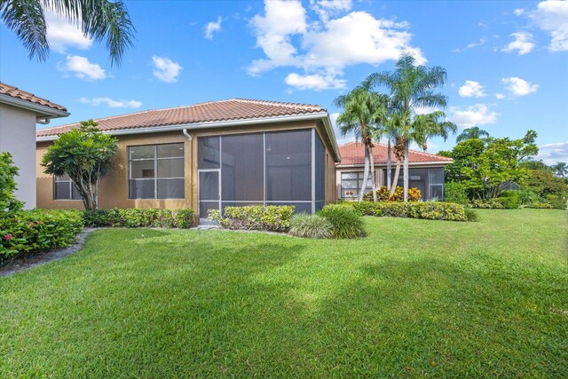 rear view of property featuring a sunroom and a lawn