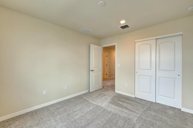 unfurnished bedroom featuring light carpet and a closet