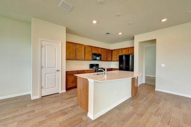 kitchen featuring black appliances, a center island with sink, and sink