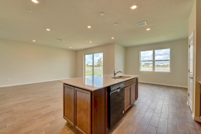 kitchen with light hardwood / wood-style floors, sink, black dishwasher, and a kitchen island with sink