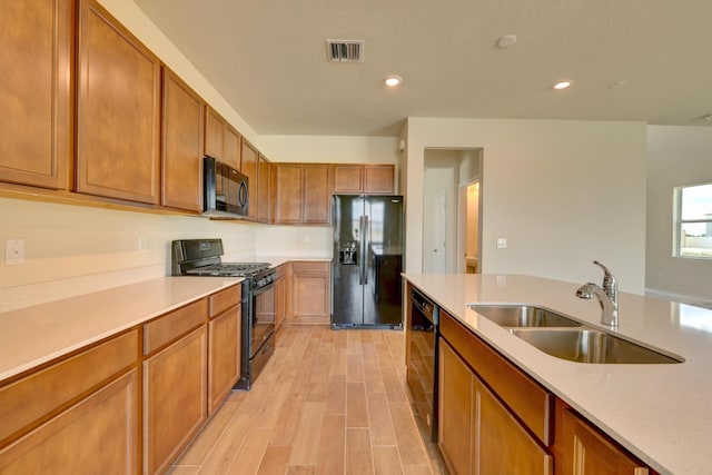 kitchen with black appliances, sink, and light hardwood / wood-style flooring