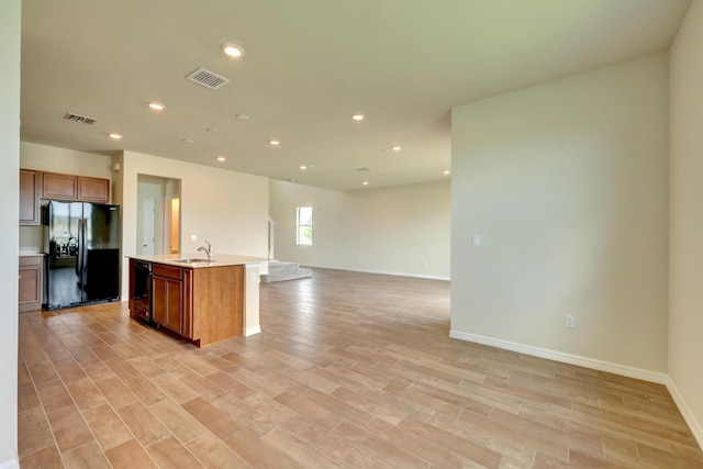 kitchen featuring sink, black appliances, a center island with sink, and light hardwood / wood-style flooring