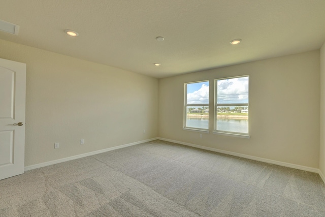 unfurnished room with a water view and light carpet