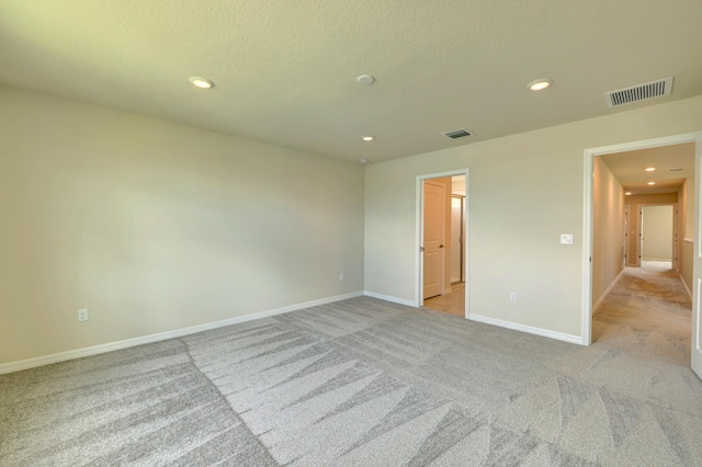 spare room with a textured ceiling and light carpet