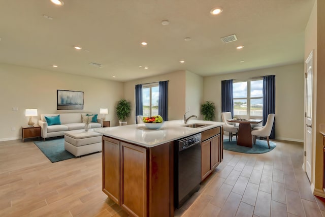 kitchen with sink, black dishwasher, a wealth of natural light, and an island with sink