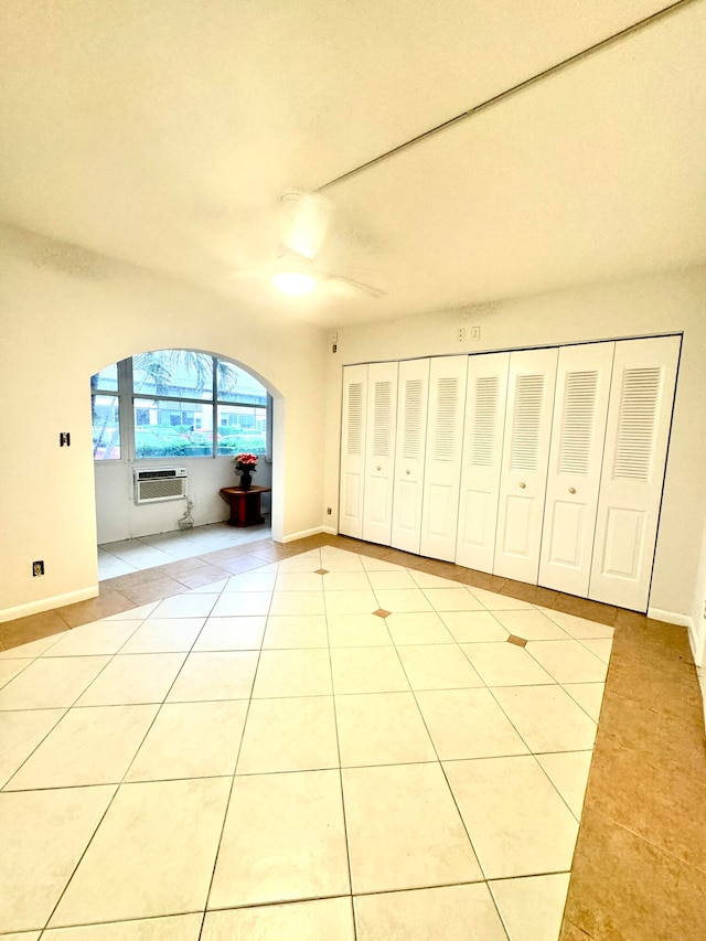 unfurnished living room with an AC wall unit, light tile patterned floors, and ceiling fan