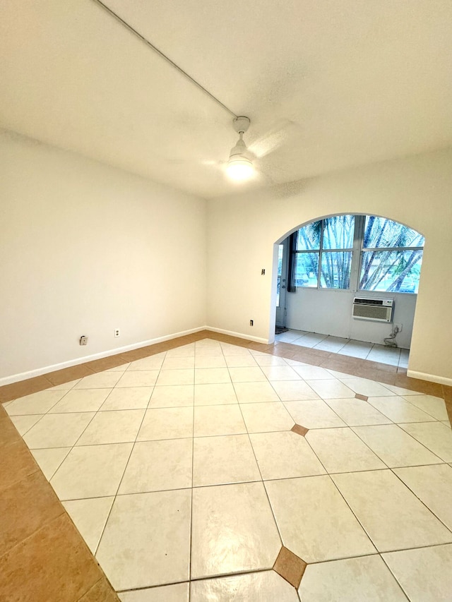 tiled spare room with an AC wall unit and ceiling fan