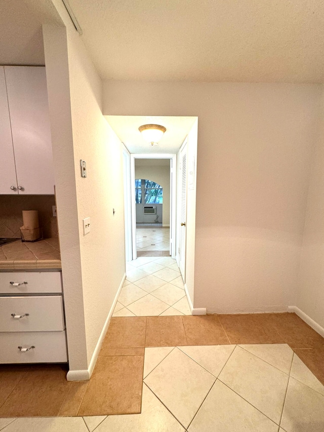 hallway featuring a textured ceiling and light tile patterned floors