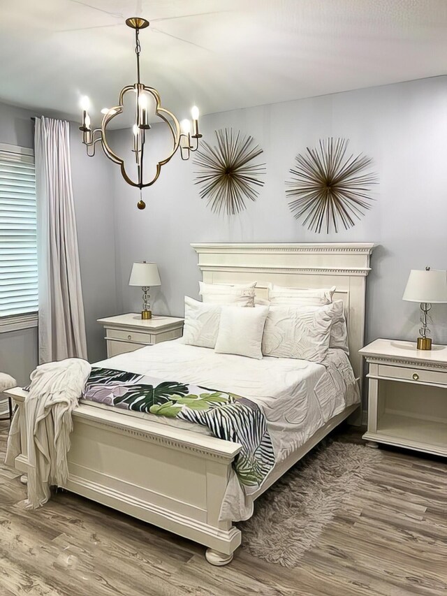 bedroom with light hardwood / wood-style floors and a notable chandelier