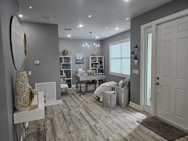 foyer entrance featuring a notable chandelier, a textured ceiling, and light wood-type flooring