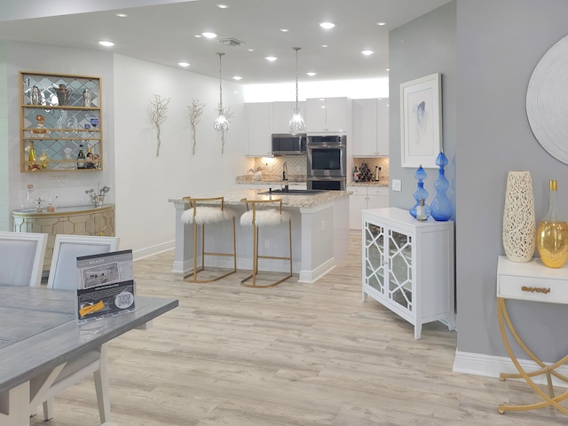 kitchen with white cabinetry, appliances with stainless steel finishes, backsplash, pendant lighting, and light stone counters