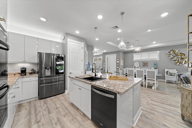 kitchen featuring an island with sink, hanging light fixtures, black appliances, white cabinets, and sink