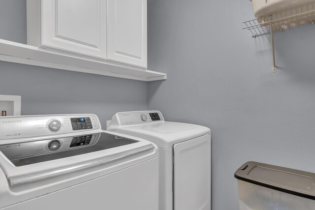 laundry room with washer and dryer and cabinets