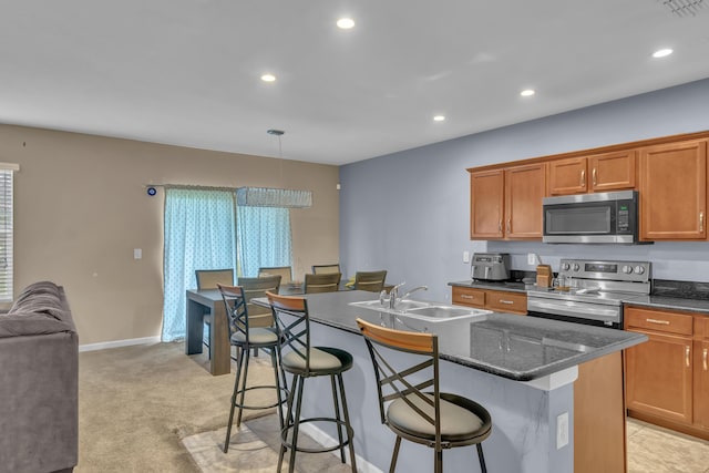 kitchen featuring appliances with stainless steel finishes, sink, a center island with sink, hanging light fixtures, and a breakfast bar area