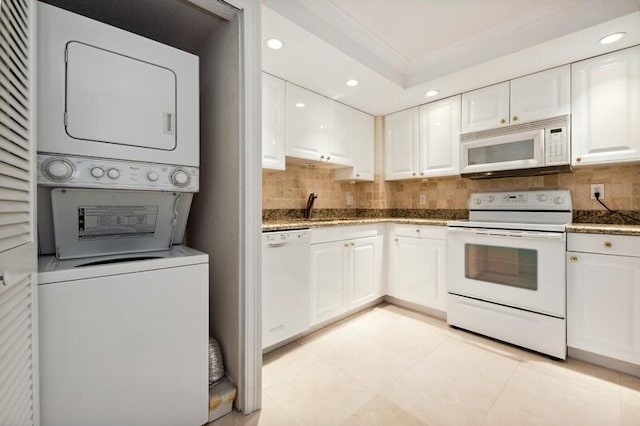 kitchen with stacked washer and dryer, tasteful backsplash, white cabinets, and white appliances