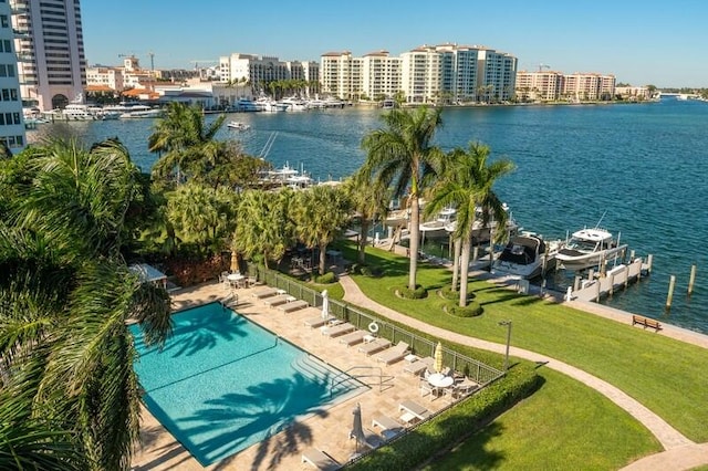 view of pool with a lawn and a water view