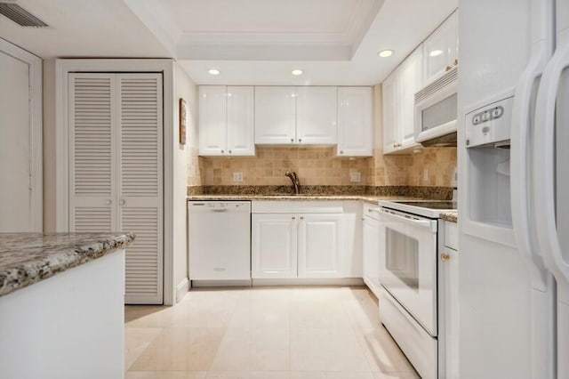 kitchen with white appliances, light stone counters, backsplash, light tile floors, and white cabinetry