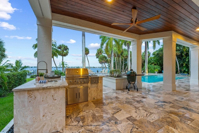 view of patio with ceiling fan, a water view, grilling area, and an outdoor kitchen