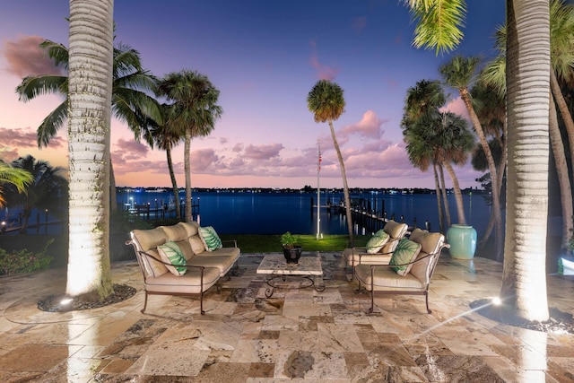 patio terrace at dusk with outdoor lounge area and a water view