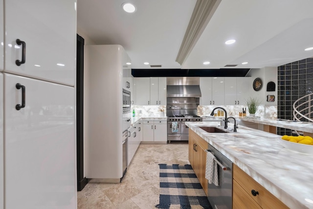 kitchen featuring white cabinetry, sink, wall chimney range hood, decorative backsplash, and appliances with stainless steel finishes