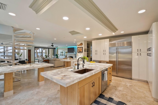 kitchen featuring a center island with sink, sink, ceiling fan, white cabinetry, and stainless steel appliances