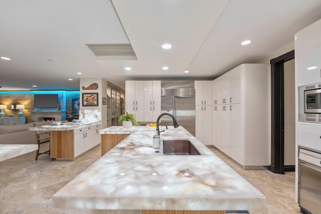 kitchen featuring built in appliances, a kitchen breakfast bar, a spacious island, and white cabinetry