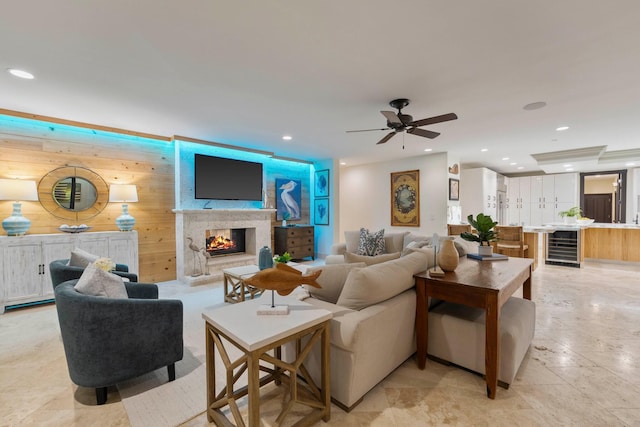 living room with a premium fireplace, beverage cooler, wooden walls, and ceiling fan