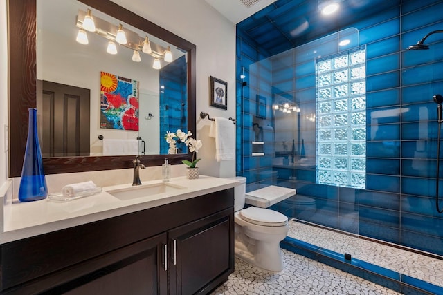 bathroom with tile patterned floors, vanity, toilet, and tiled shower